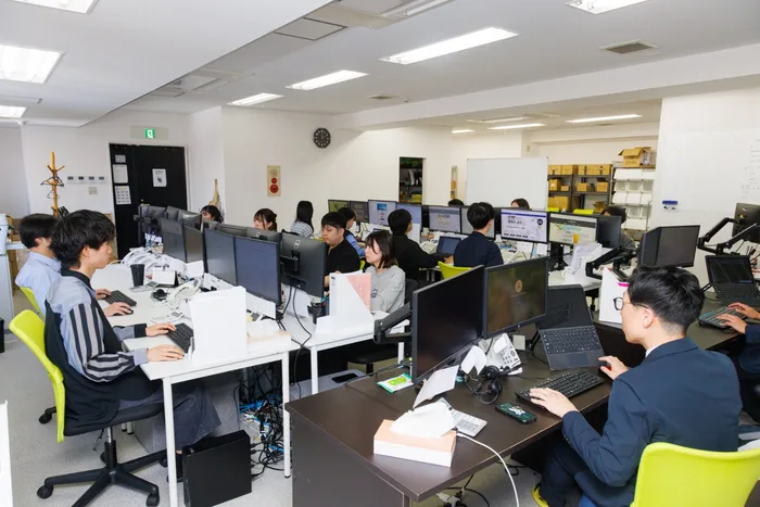 複数台のモニターに向かいながら業務にあたるオフィスの社員たち